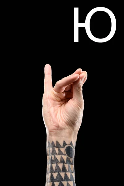 Male tattooed hand showing cyrillic letter, sign language, isolated on black — Stock Photo