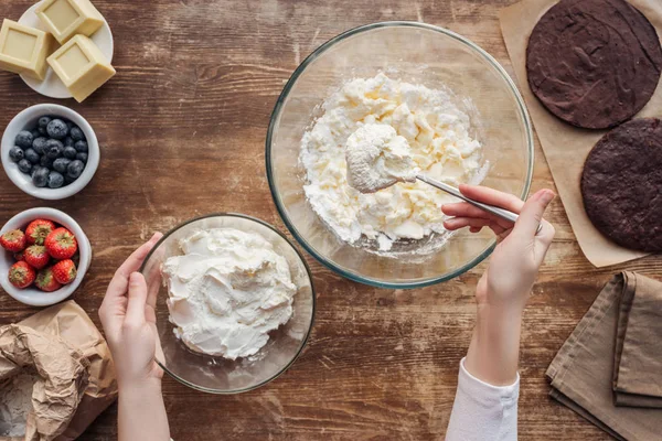 Tiro recortado de la mujer que prepara la masa y la crema para el pastel delicioso - foto de stock