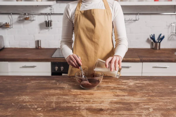 Abgeschnittene Aufnahme einer Frau in Schürze, die Zutaten mixt und köstlichen süßen Kuchen zubereitet — Stockfoto