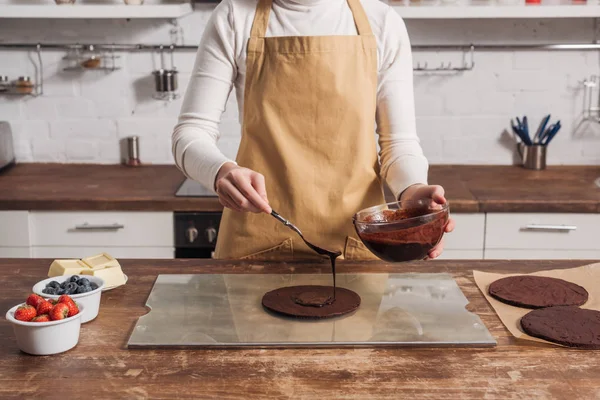 Обрізаний знімок жінки в фартусі готує гастрономічний солодкий торт на кухні — стокове фото