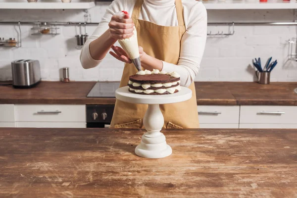 Tiro recortado de mujer en delantal decorando pastel de pastel de whoopie con crema - foto de stock