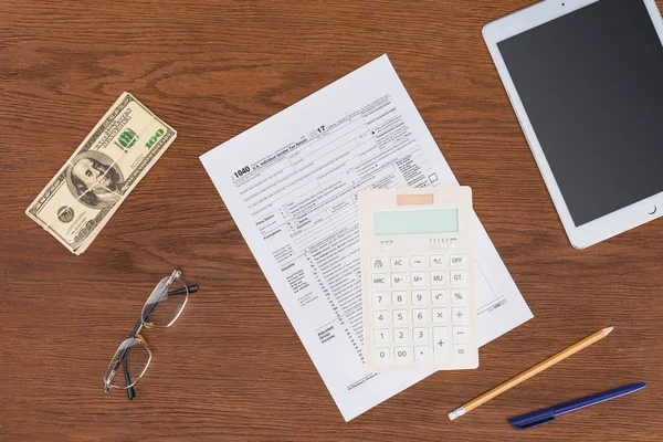 Vista superior da forma fiscal, calculadora e nota de dólar na mesa de madeira no local de trabalho — Fotografia de Stock
