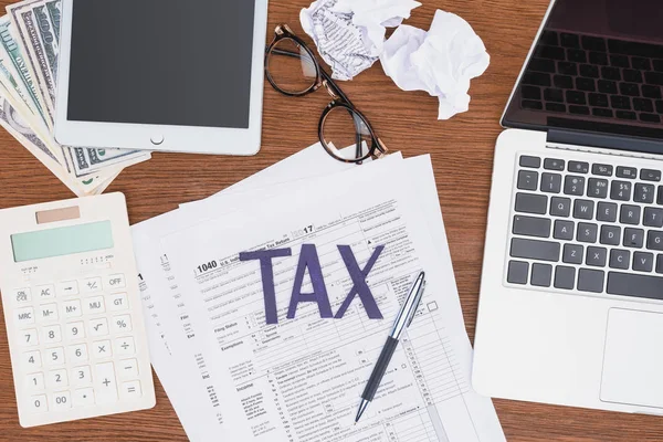 Top view of tax forms, digital devices and crumpled paper balls on desk — Stock Photo