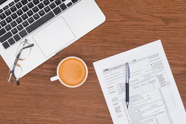 Vue du haut du formulaire d'impôt, ordinateur portable, notes collantes et café sur le bureau — Photo de stock