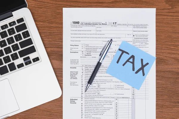 Top view of tax form, laptop and blue card with 'tax' word on desk — Stock Photo