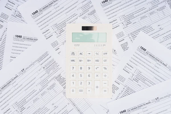 Top view of white calculator with tax forms on background — Stock Photo