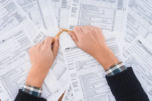 Cropped view of stressed man breaking pencil with tax forms on background — Stock Photo