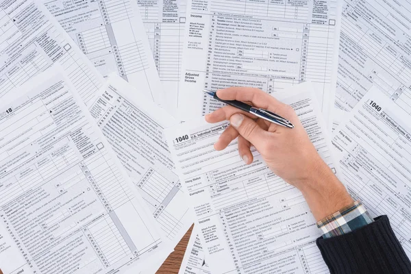 Vue partielle de l'homme tenant un stylo et remplissant les formulaires fiscaux avec espace de copie — Photo de stock