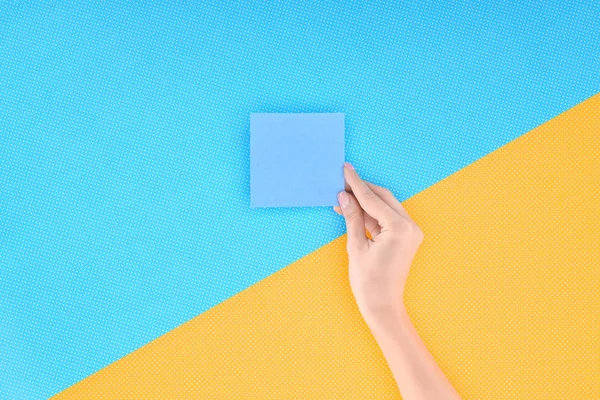 Ausgeschnittene Ansicht einer Frau mit leerer blauer Karte auf blauem und gelbem Hintergrund — Stockfoto