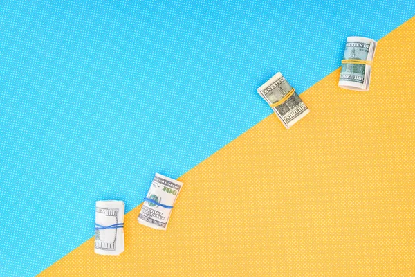 Вид зверху грошових рулонів на синьо-жовтому фоні з копіювальним простором — стокове фото