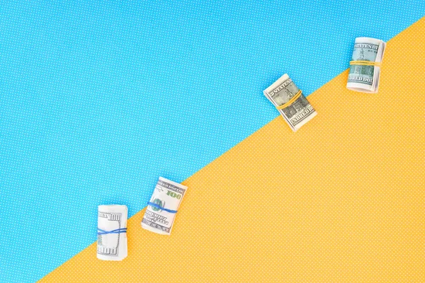 Top view of money rolls on blue and yellow background with copy space — Stock Photo