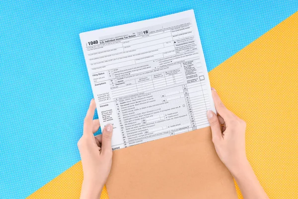 Vista recortada del formulario de retención de impuestos de la mujer sobre fondo azul y amarillo - foto de stock