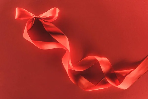 Вид зверху на червоний святковий стрічковий лук ізольований на червоному, концепція дня Святого Валентина — стокове фото