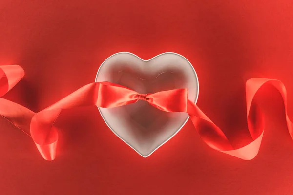 Vista elevada del símbolo del corazón y cinta festiva aislado en rojo, San Valentín concepto de día - foto de stock