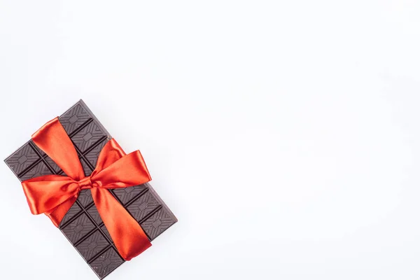 Vue d'en haut de délicieux chocolat enveloppé par un ruban festif isolé sur blanc, concept St Valentin — Photo de stock