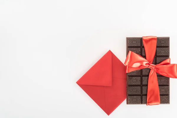 Вид зверху конверта і смачний шоколад, загорнутий святковою стрічкою, ізольований на білому, концепція дня Святого Валентина — стокове фото