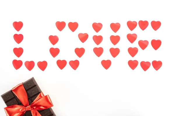 Flat lay with lettering love made of heart symbols and chocolate wrapped by festive ribbon isolated on white, st valentine day concept — Stock Photo