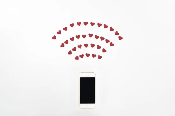 Vista superior símbolos de corazón rojo y teléfono inteligente con pantalla en blanco aislado en blanco, San Valentín concepto de día - foto de stock