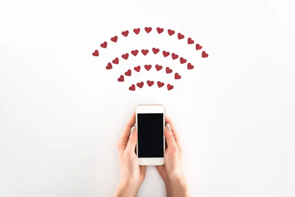 Vista parziale della donna utilizzando smartphone con schermo bianco sotto i simboli del cuore rosso isolati sul bianco, concetto di giorno di San Valentino — Foto stock