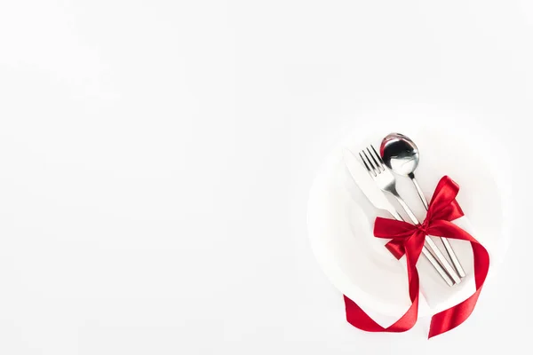 Vue d'en haut de l'assiette avec couverts enveloppés par un ruban festif isolé sur blanc, concept St Valentin — Photo de stock