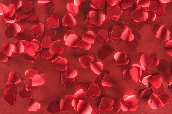 Belas pétalas decorativas em forma de coração no fundo vermelho, conceito dia dos namorados — Fotografia de Stock