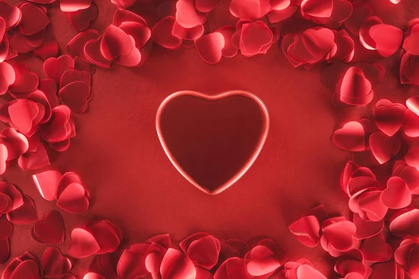 Vista superior de hermoso corazón y pétalos decorativos sobre fondo rojo, concepto de día de San Valentín - foto de stock