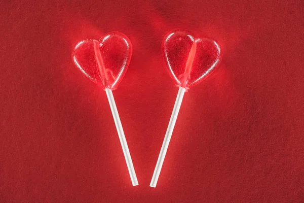 Vista de cerca de piruletas en forma de corazón sobre fondo rojo, concepto de día de San Valentín - foto de stock