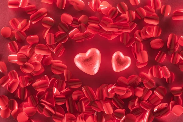 Vue du haut de deux cœurs rouges et de beaux pétales décoratifs, fond de la Saint-Valentin — Photo de stock