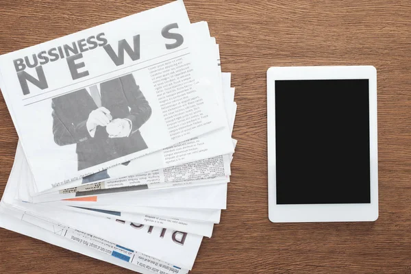 Vista superior do tablet com tela em branco e jornais de negócios em mesa de madeira — Fotografia de Stock