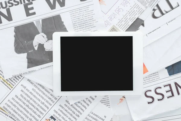 Vista superior de la tableta con pantalla en blanco en los periódicos de negocios - foto de stock