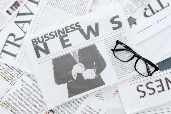 Top view of business newspapers and eyeglasses on surface — Stock Photo