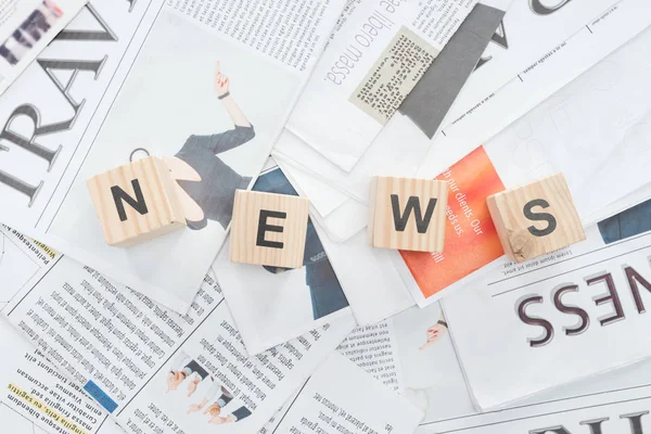Elevated view of wooden cubes with word news on newspapers — Stock Photo