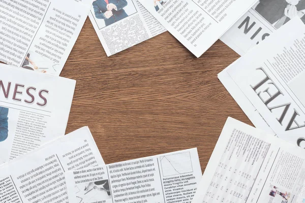 Elevated view of different newspapers on wooden tabletop — Stock Photo