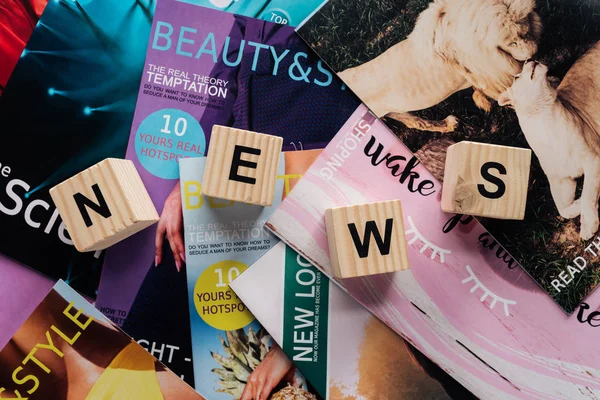 Vue de dessus de pile de différents magazines tabloïd et cubes en bois avec des nouvelles de mot sur la surface — Photo de stock