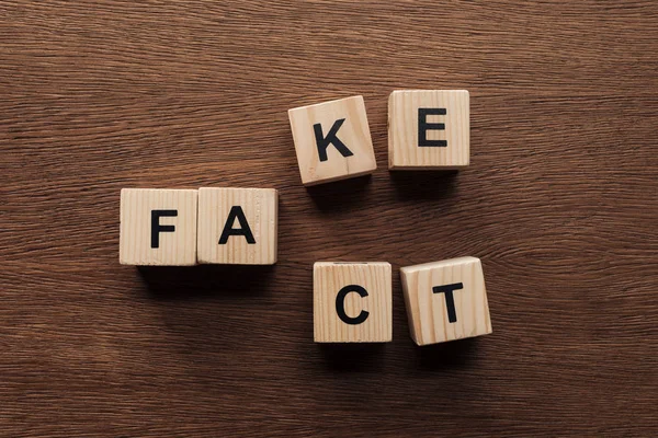 Draufsicht auf Holzwürfel mit Wörtern fake fact tabletop — Stockfoto