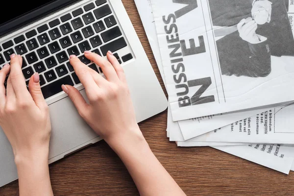 Image recadrée d'un journaliste travaillant sur un ordinateur portable à une table en bois — Photo de stock