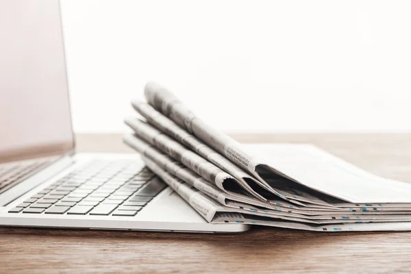 Laptop und Zeitungsstapel auf Holztischplatte — Stockfoto