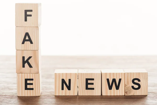 Cubos de madera con palabras noticias falsas en la mesa de madera - foto de stock