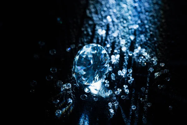Diamantes grandes e pequenos no fundo escuro com luz — Fotografia de Stock
