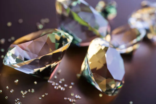 Enfoque selectivo de diamantes grandes y pequeños sobre fondo marrón - foto de stock