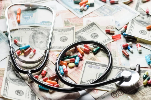 Close up of colorful pills and stethoscope on money background — Stock Photo