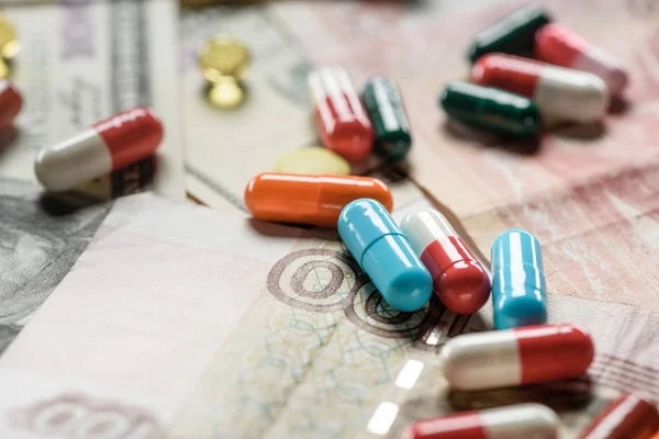Крупним планом різнокольорові таблетки на грошовому фоні — стокове фото