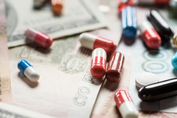 Selective focus of bright pills on money background — Stock Photo