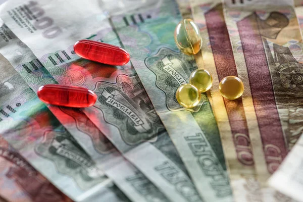 Close up of red oval and yellow round pills on money background — Stock Photo