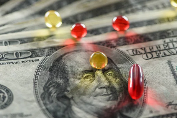 Close up of bright oval and round pills on dollars background — Stock Photo