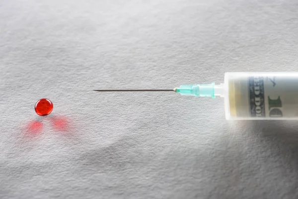 Gros plan de la seringue avec injection d'argent et pilule ronde rouge sur fond gris — Photo de stock