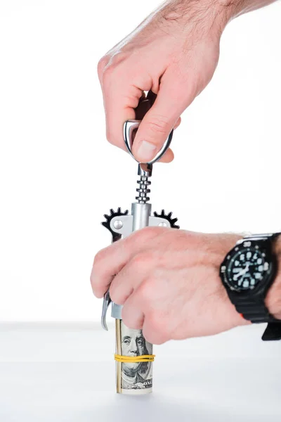 Cropped view of man using corkscrew with money roll on blurred white and grey background — Stock Photo