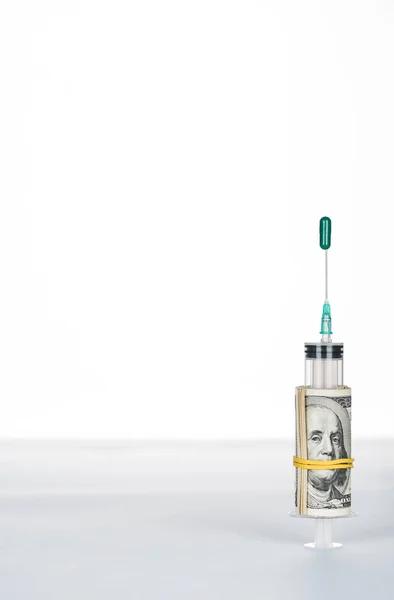 Rotolo di denaro e siringa con pillola ovale verde su ago isolato su bianco — Foto stock