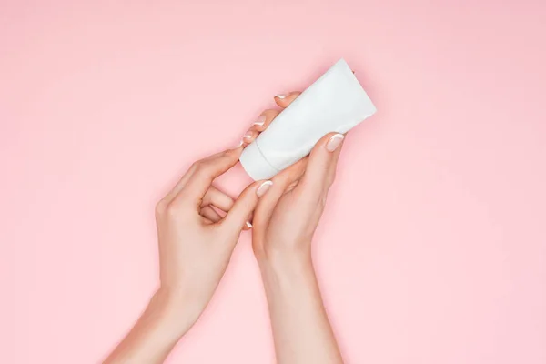 Vista recortada de las manos femeninas con crema de manos aislada en rosa - foto de stock