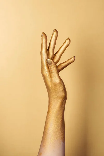 Vista recortada de la mano pintada femenina sobre fondo dorado - foto de stock